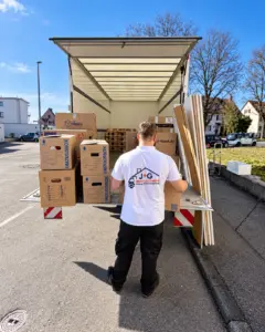 J+G Mitarbeiter bei einem Umzug mit Kartons vor einem Transportfahrzeug
