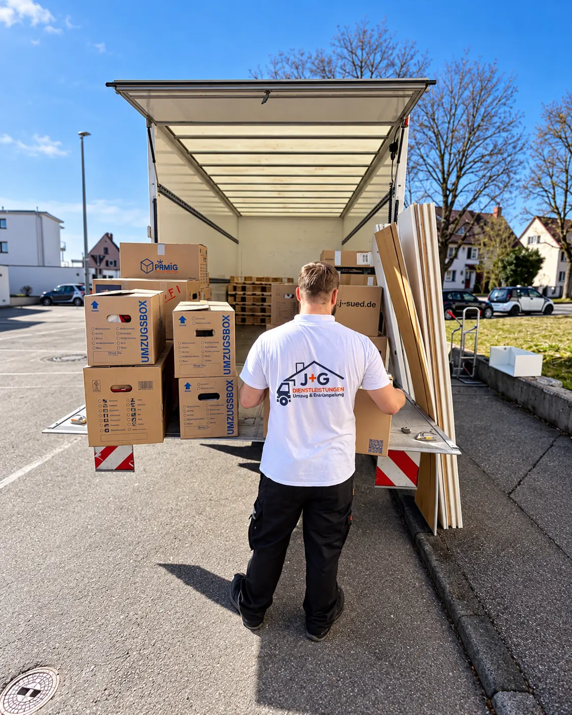 J+G Mitarbeiter bei einem Umzug mit Kartons vor einem Transportfahrzeug